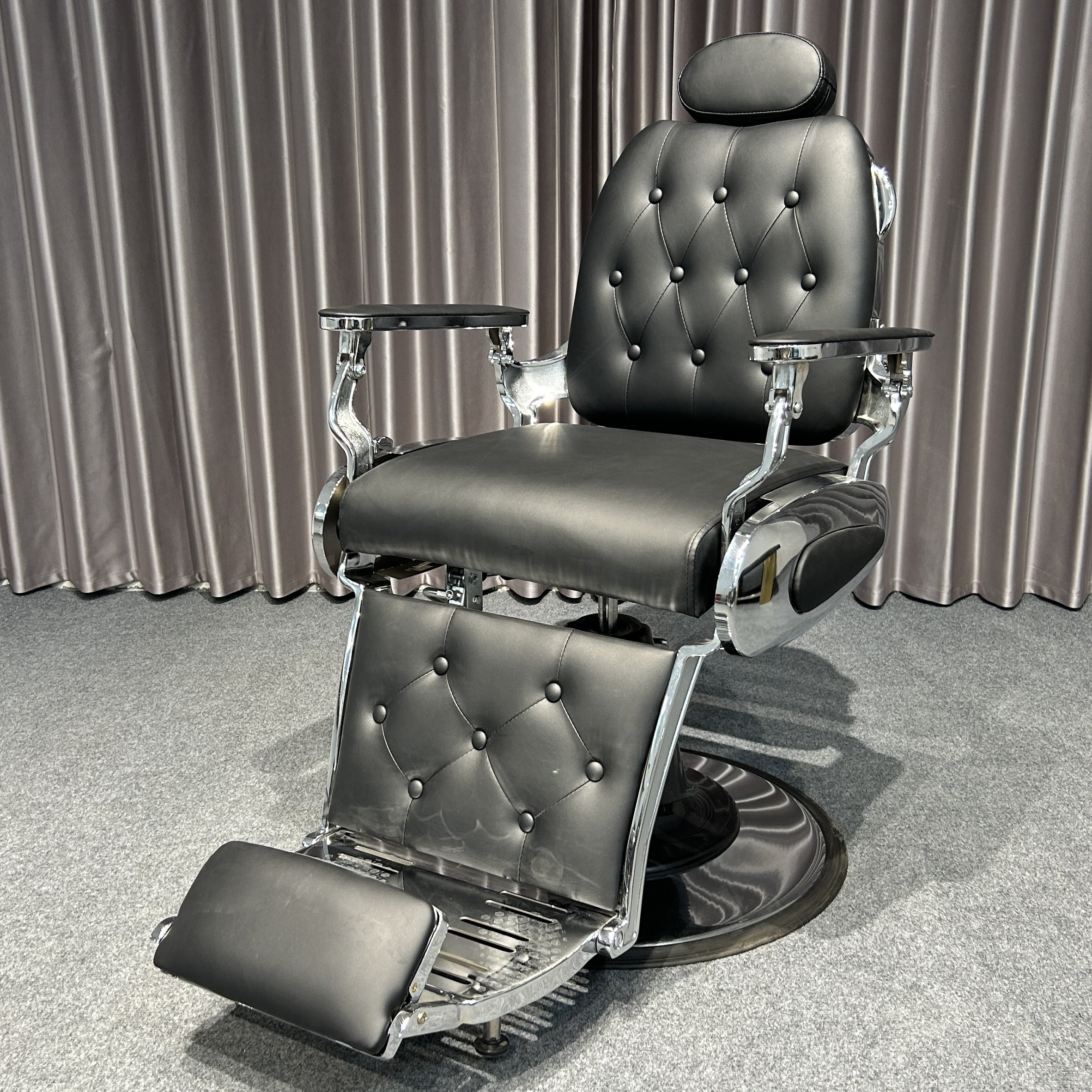 The classic black ergonomic barber chair rotates and lifts the barbershop with metal equipment and silver trim