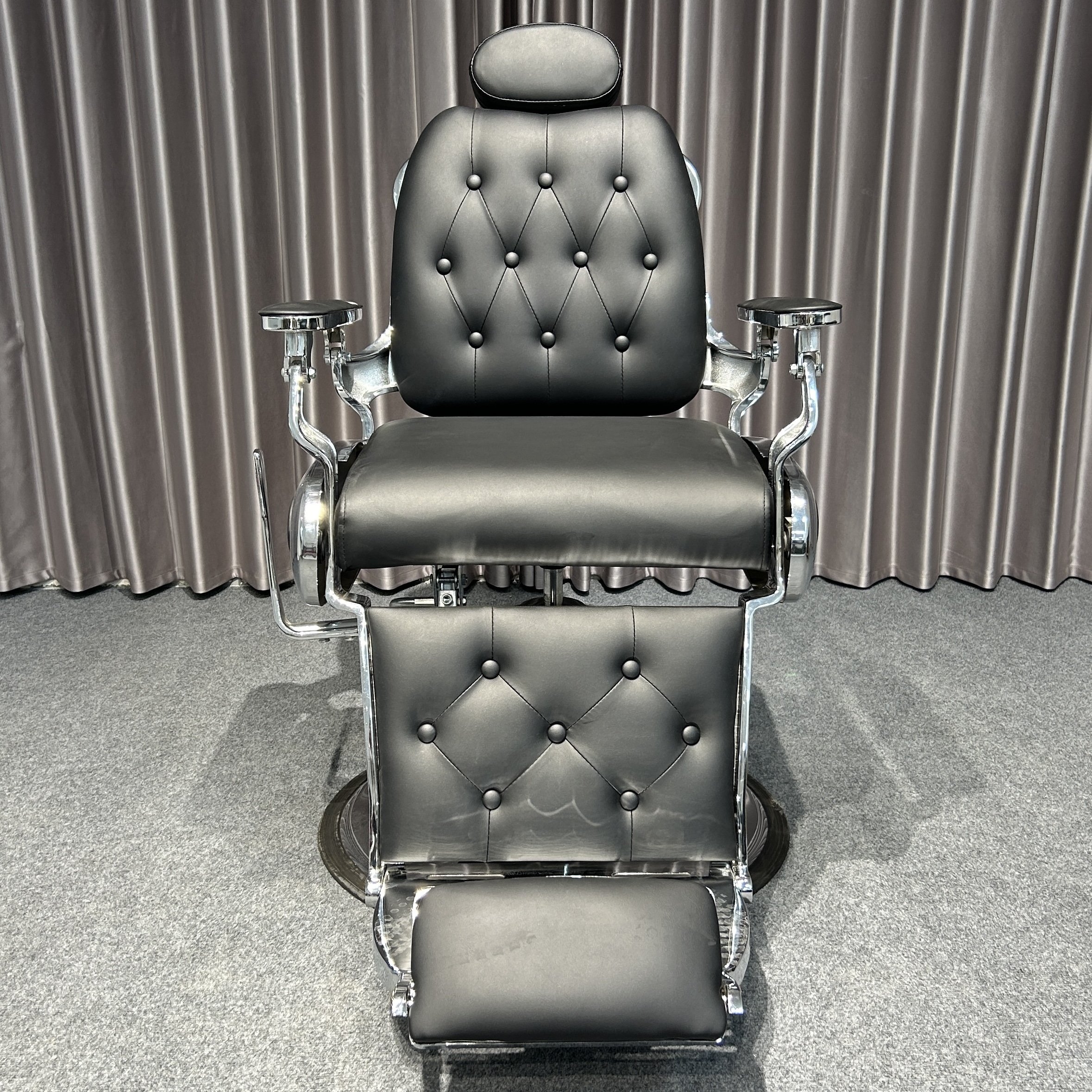 The classic black ergonomic barber chair rotates and lifts the barbershop with metal equipment and silver trim