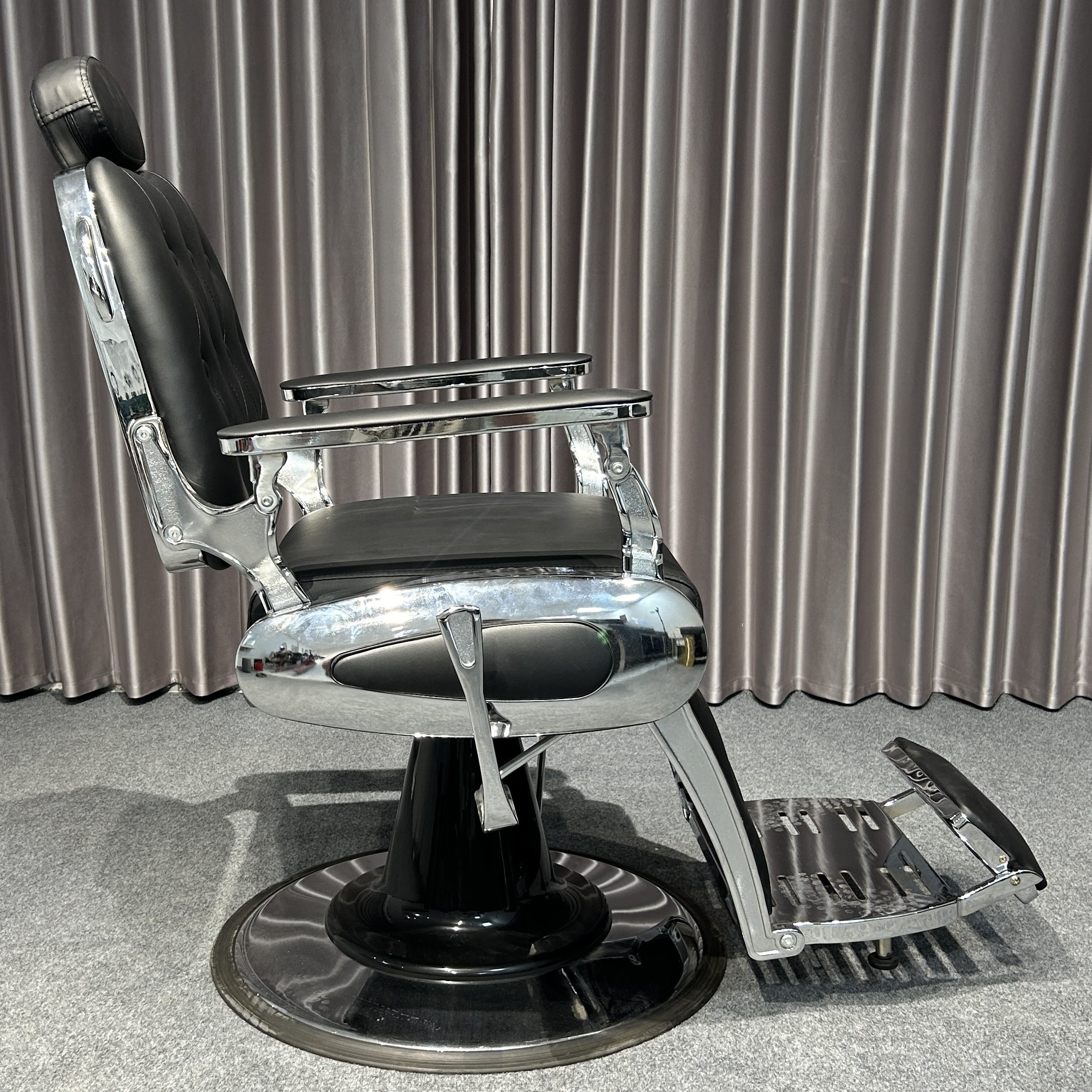 The classic black ergonomic barber chair rotates and lifts the barbershop with metal equipment and silver trim