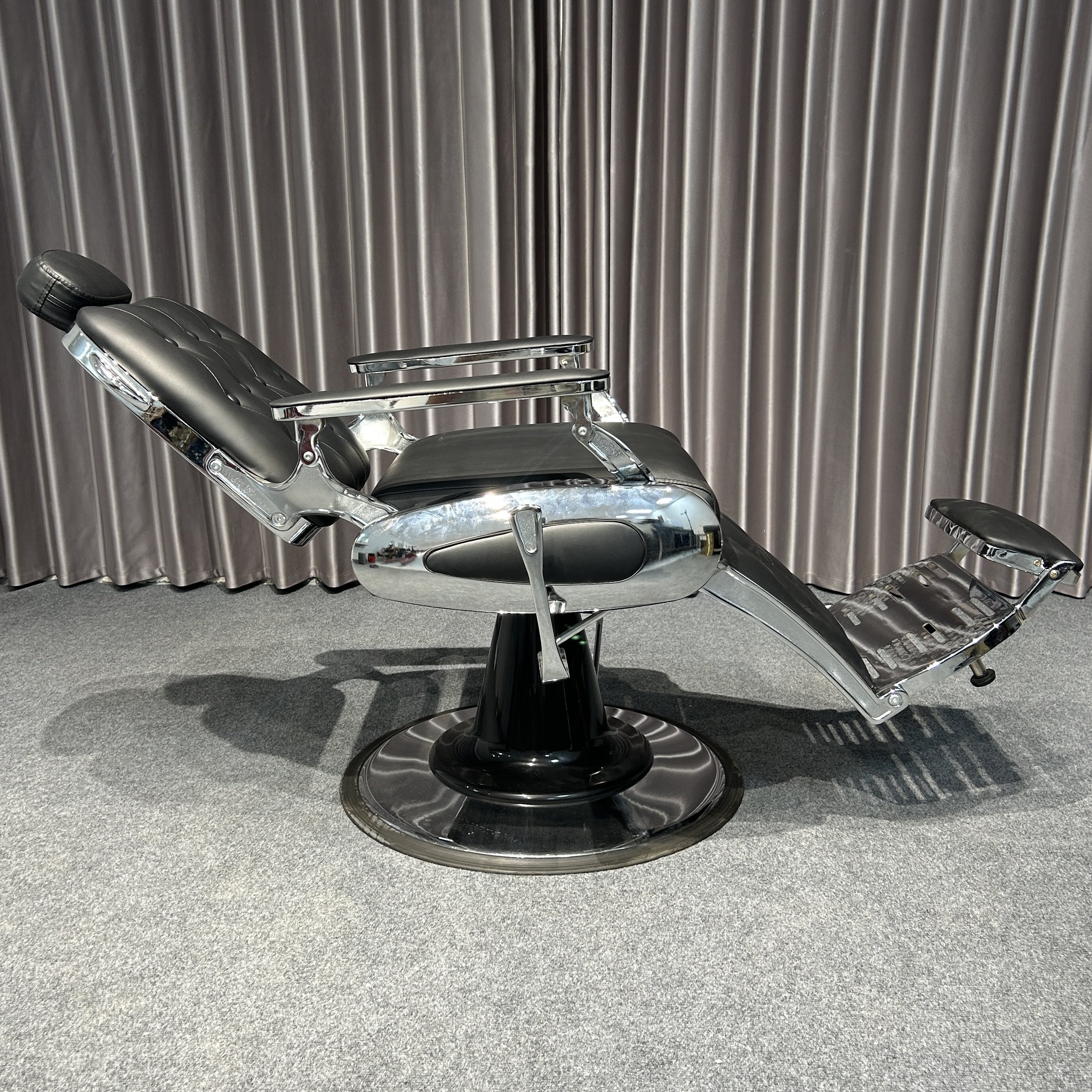 The classic black ergonomic barber chair rotates and lifts the barbershop with metal equipment and silver trim