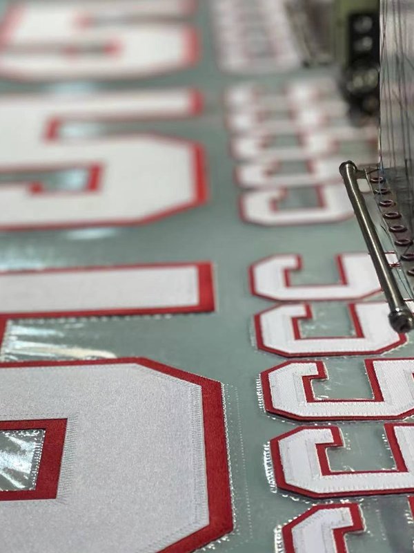Factory Directly Sell HotMelt Adhesive Backing Team Colors Poly Twill Embroidery Applique Tackle Twill for Sports Jersey