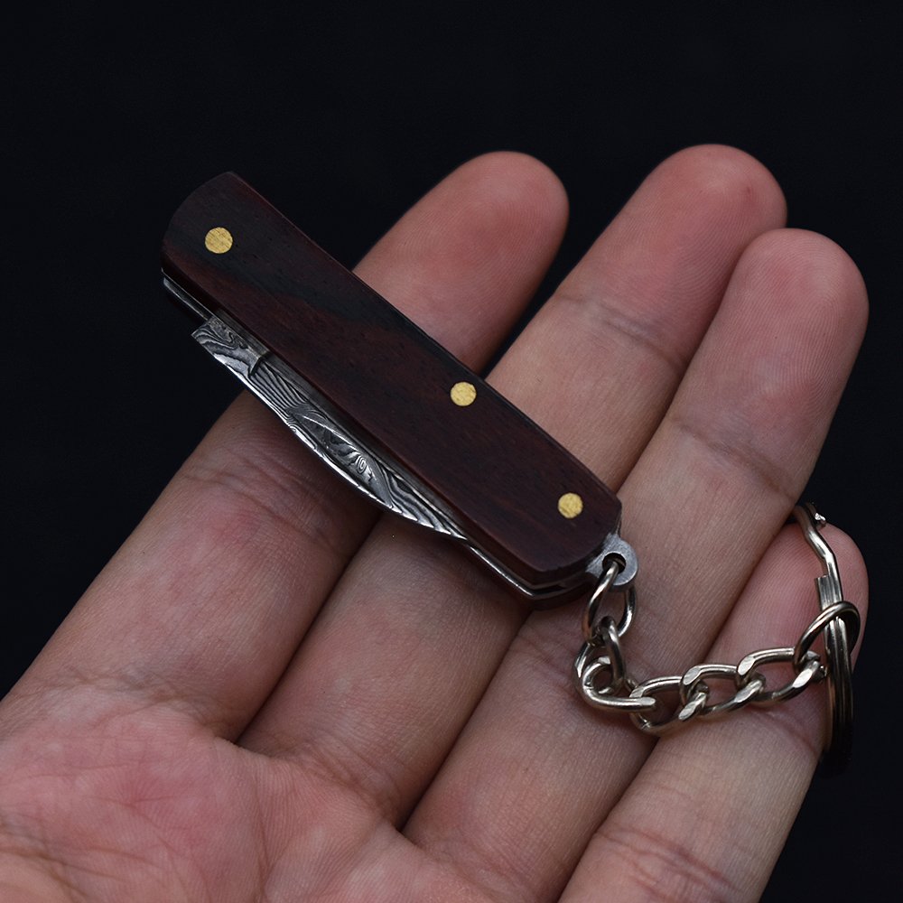 A small, folding knife, a practical fielding knife and a key-button with a mini-Damascus knife