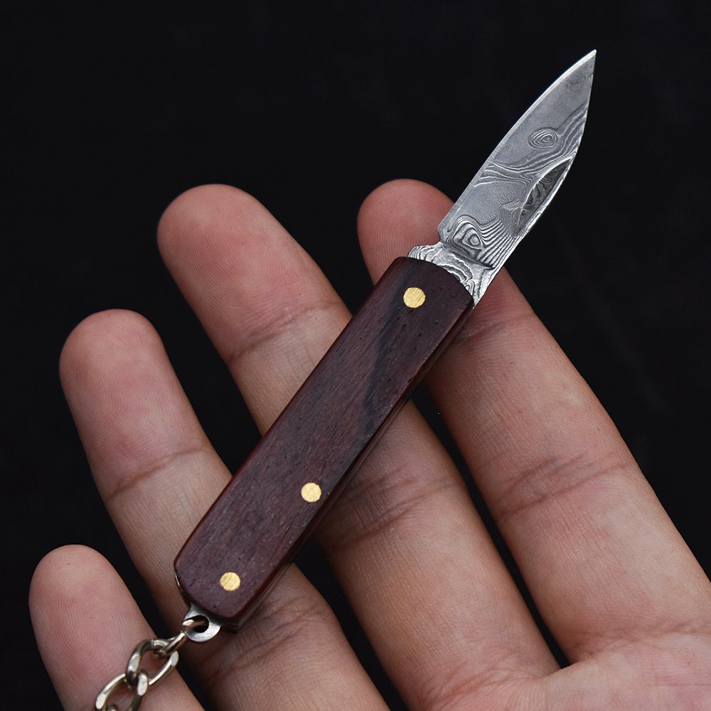 A small, folding knife, a practical fielding knife and a key-button with a mini-Damascus knife