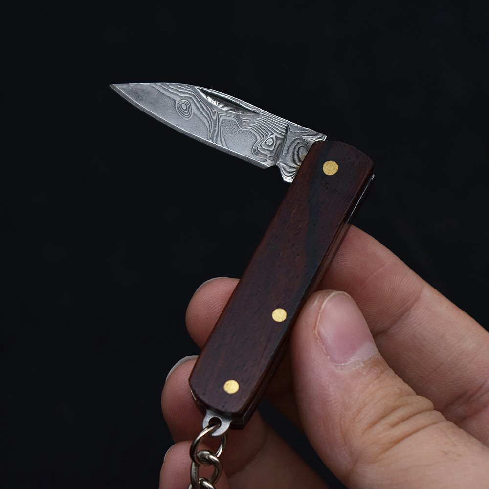 A small, folding knife, a practical fielding knife and a key-button with a mini-Damascus knife