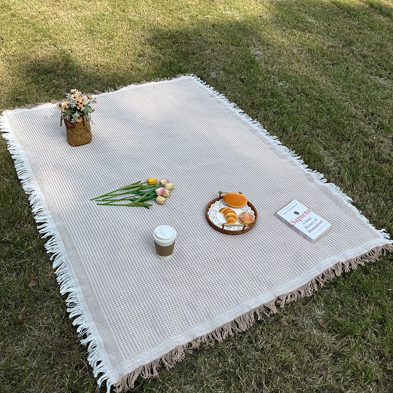 An outdoor picnic pad with a linen table and a blanket for a blanket