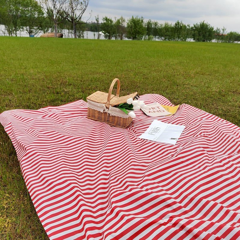 a striped picnic on a beach with a waterproof, sand-proof, open-sea-side camping pavilion with a tablecloth