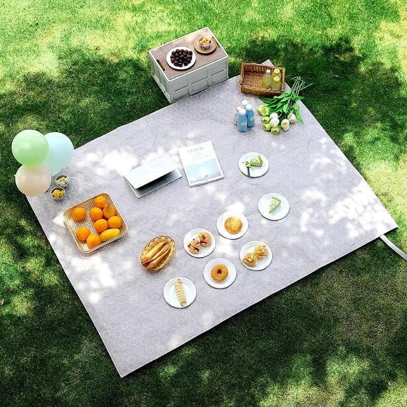 A picnic mat with a thick outdoor tent and a spring camping camper and a water-proof beach mat