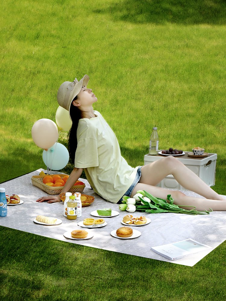 A picnic mat, a damp and grass-painted camp outside the park, carries a sand-paste