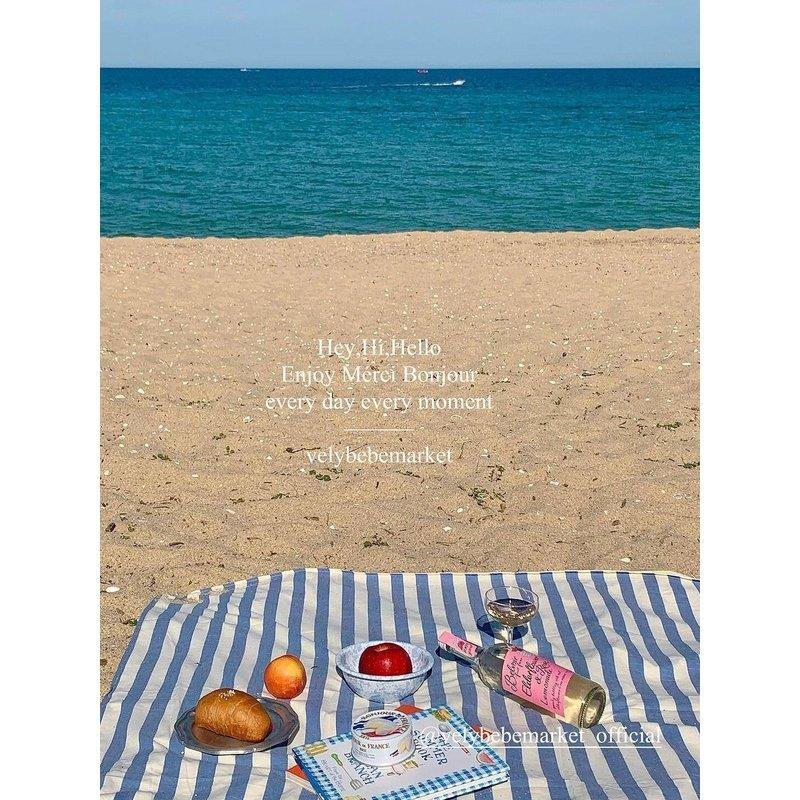 a striped picnic on a beach with a waterproof, sand-proof, open-sea-side camping pavilion with a tablecloth