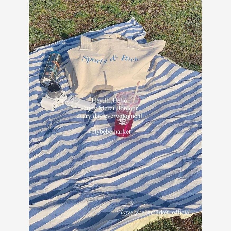 a striped picnic on a beach with a waterproof, sand-proof, open-sea-side camping pavilion with a tablecloth