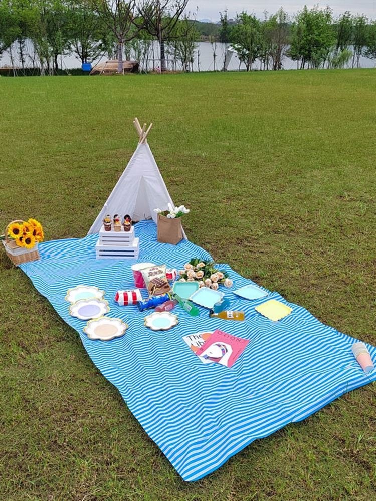 a striped picnic on a beach with a waterproof, sand-proof, open-sea-side camping pavilion with a tablecloth