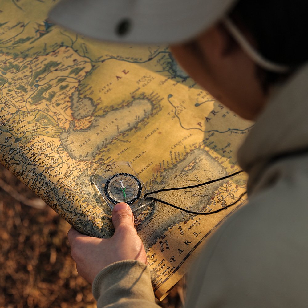 A professional multi-purpose compass for outdoor equipment in the wilderness points to a scale-scale compass of the north map