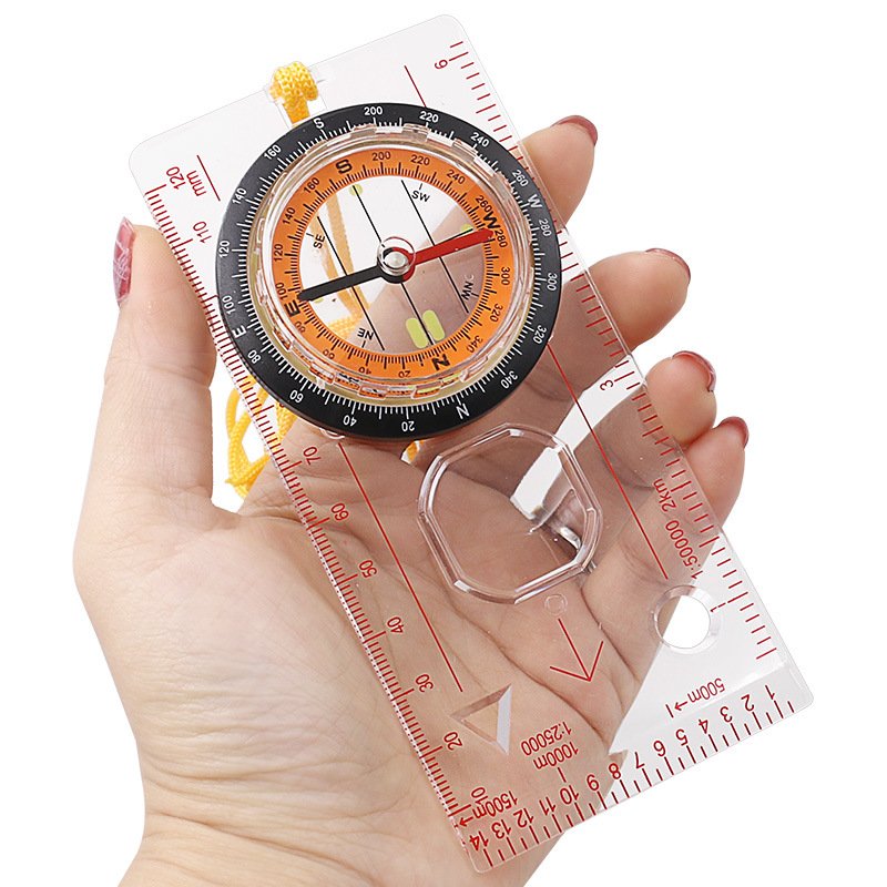 A multi-purpose map ruler guide to a field camping tool points to the north for an emergency