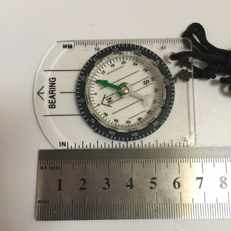 An outdoor multifunctional and transparent portable compass with a map of the compass and a northerly pointer