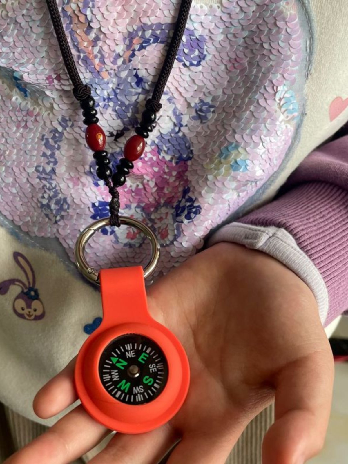 An outdoor navigation compass key to a necklace guide to a child student experiment with a northerly pointer