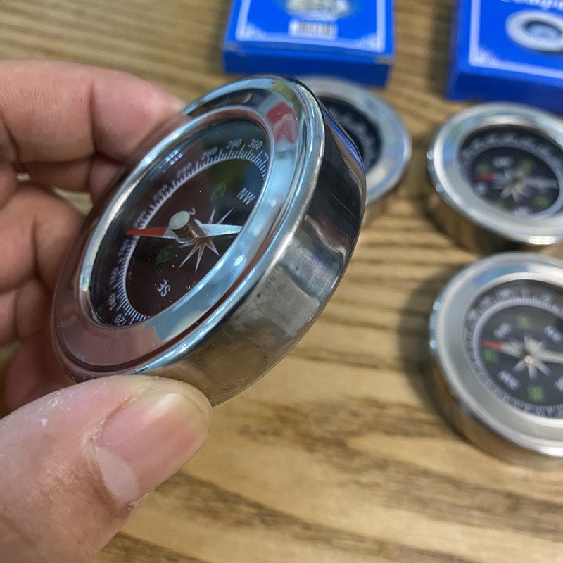 A compass, a metal shell, a hand-held metallic stainless steel pointer in an outdoor mountain trip
