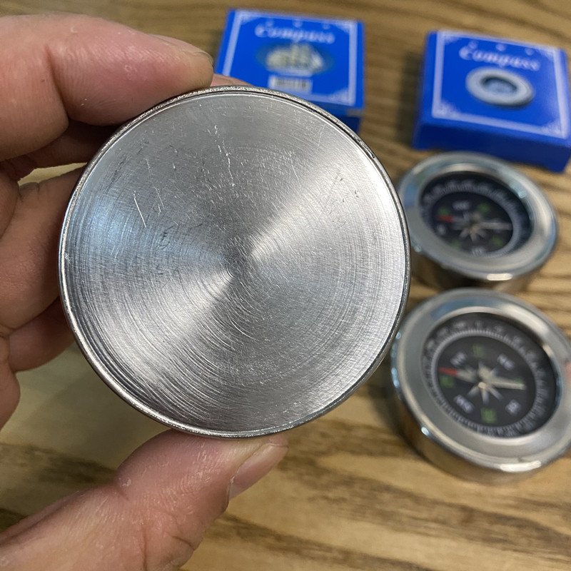 A compass, a metal shell, a hand-held metallic stainless steel pointer in an outdoor mountain trip