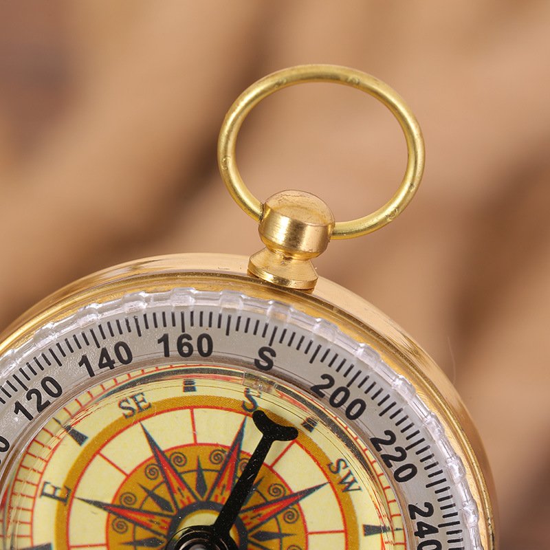 An emergency retrograde copper compass points north to a brass compass and travels outdoor camping supplies