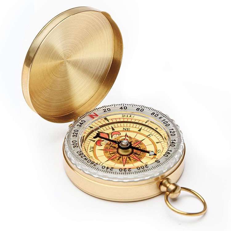 An emergency retrograde copper compass points north to a brass compass and travels outdoor camping supplies