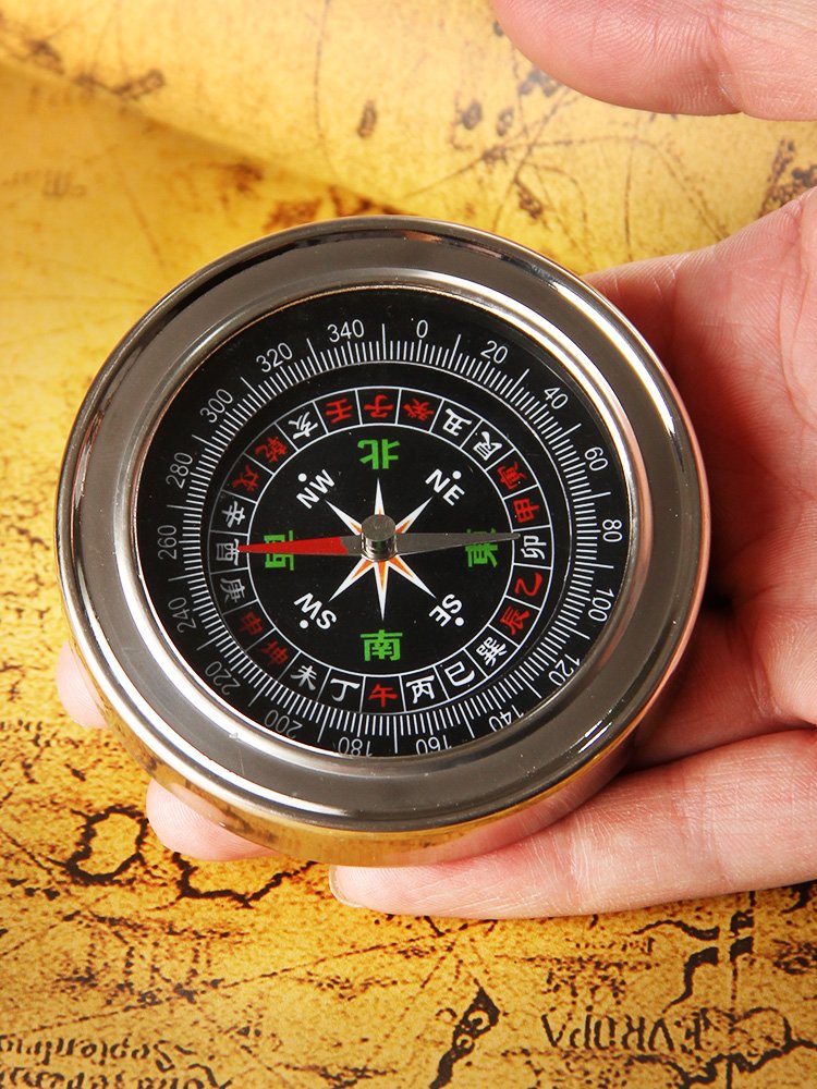 An outdoor multi-purpose compass with an adult children's sports climber with a big finger to the northern compass