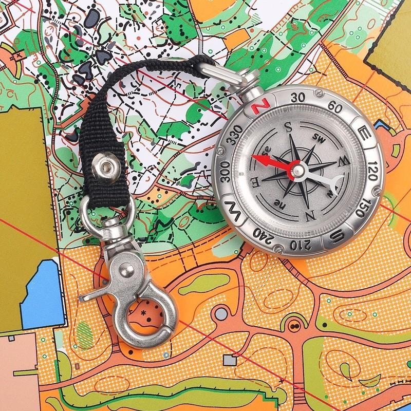 Portable multi-purpose key button guide to an outdoor camping tool compass pointing north to survival