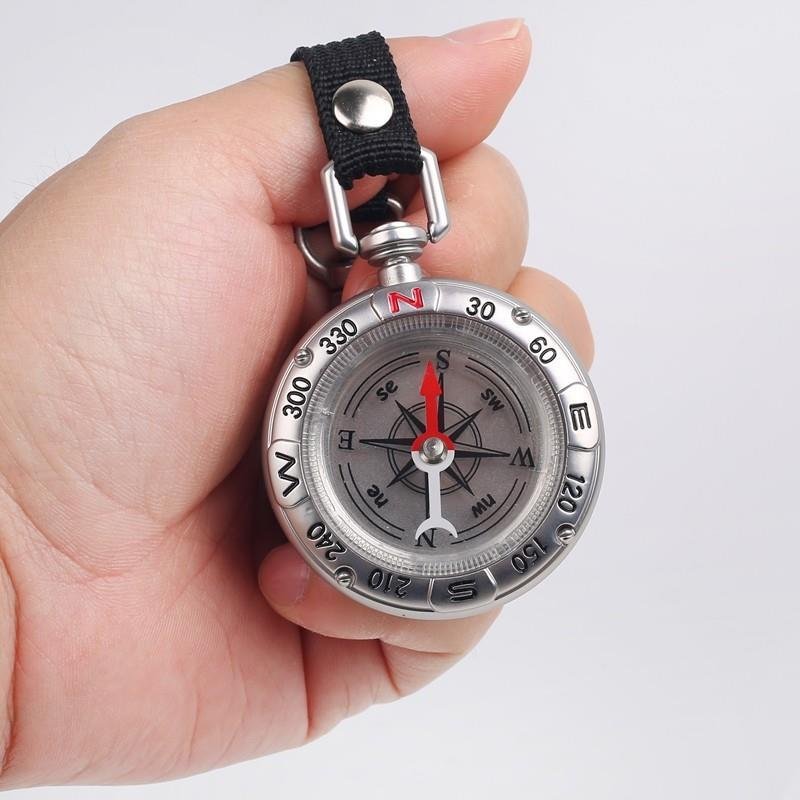 Portable multi-purpose key button guide to an outdoor camping tool compass pointing north to survival