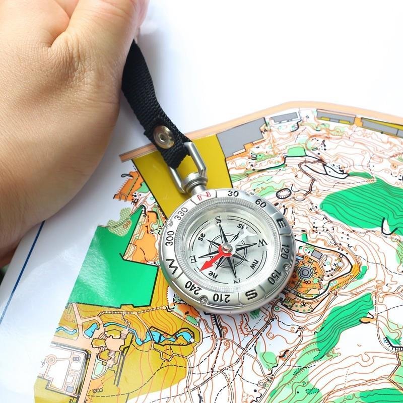 Portable multi-purpose key button guide to an outdoor camping tool compass pointing north to survival