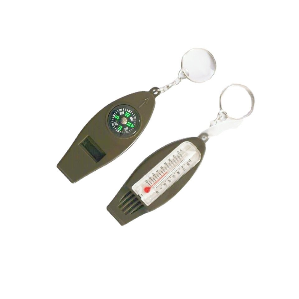A multi-purpose whistle with a magnifying glass thermometer outside the perimeter of a four-point compass