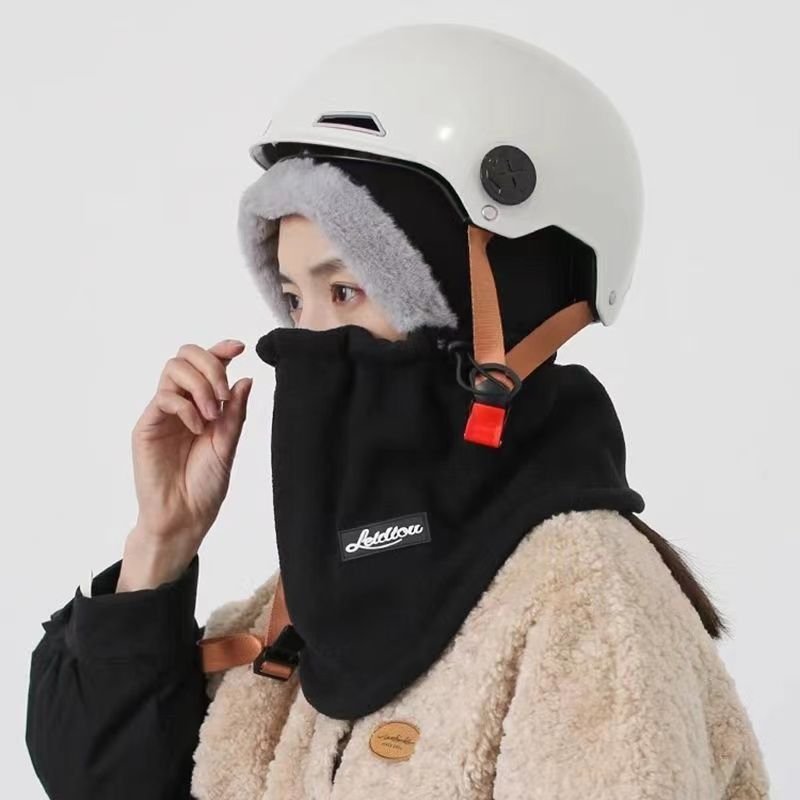 In winter, a woman with a warm head cap rides an electric car around with a decent ski mask and a cold neck scarf