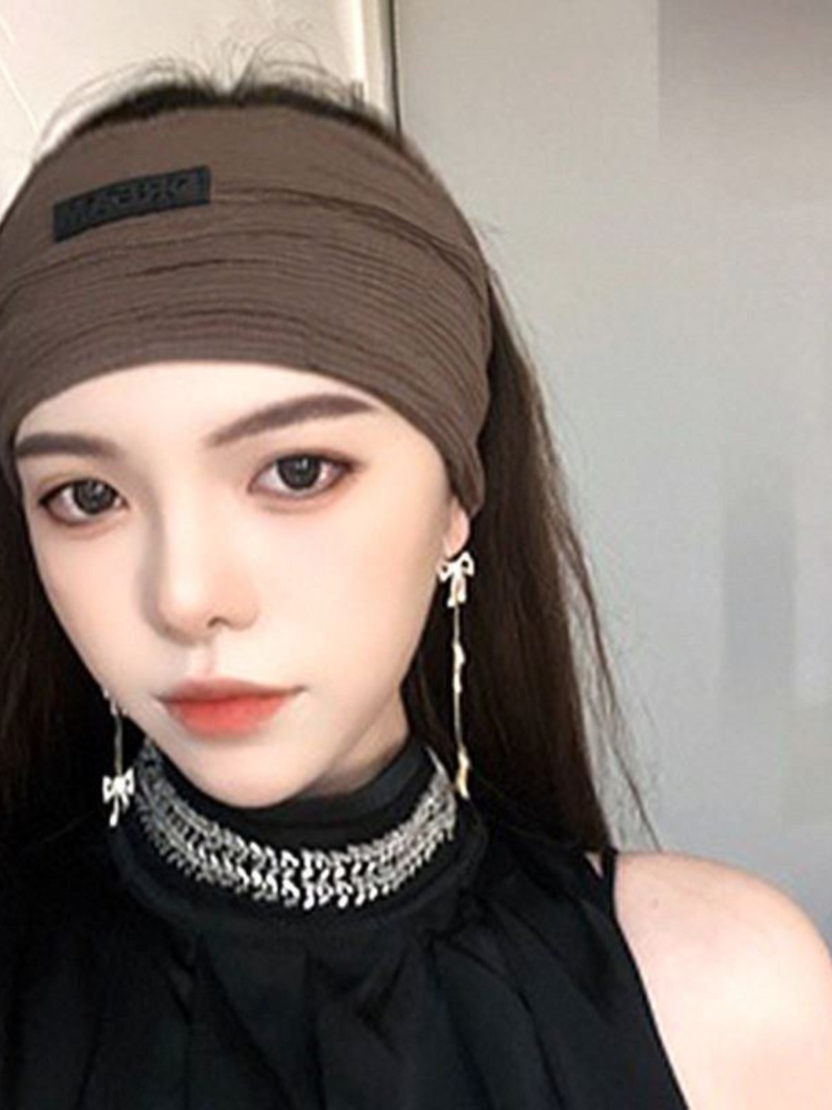 She wears a turban with a hat on her hair and a hair on her face