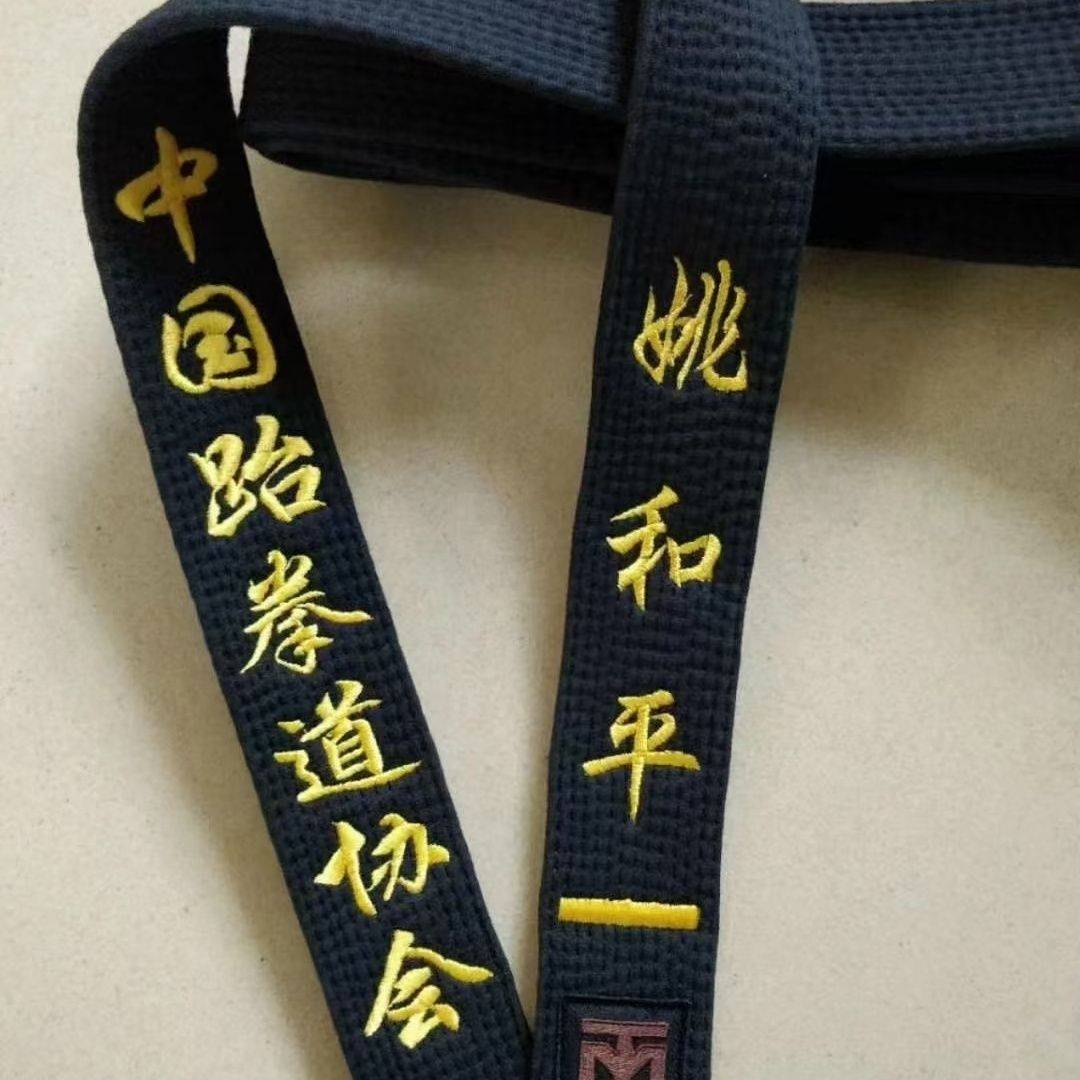 Taekwondo belts with children embroidered, black-banded athletes scattered with their coach's black-band karate belt