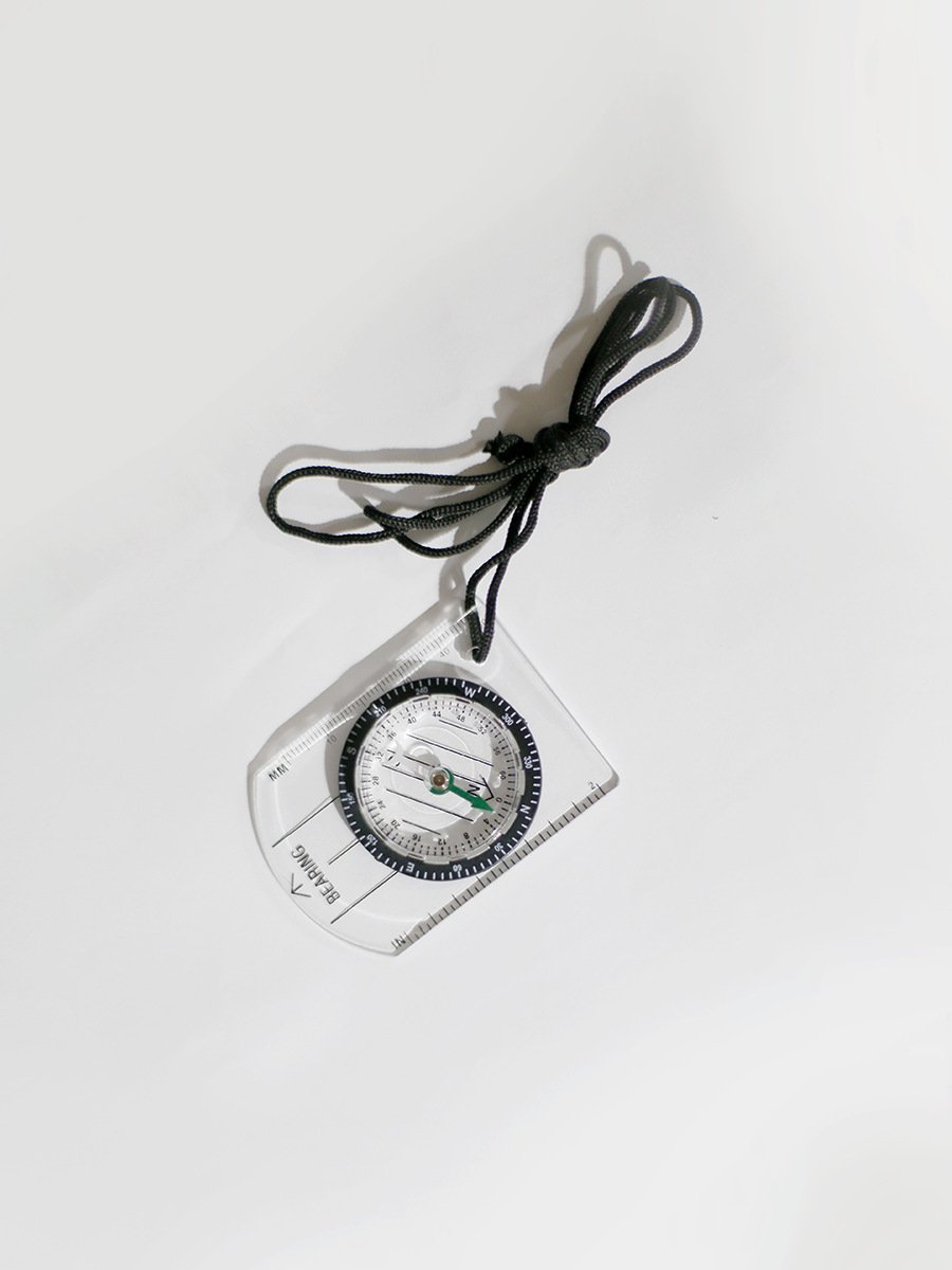 A professional multi-purpose compass for outdoor equipment in the wilderness points to a scale-scale compass of the north map