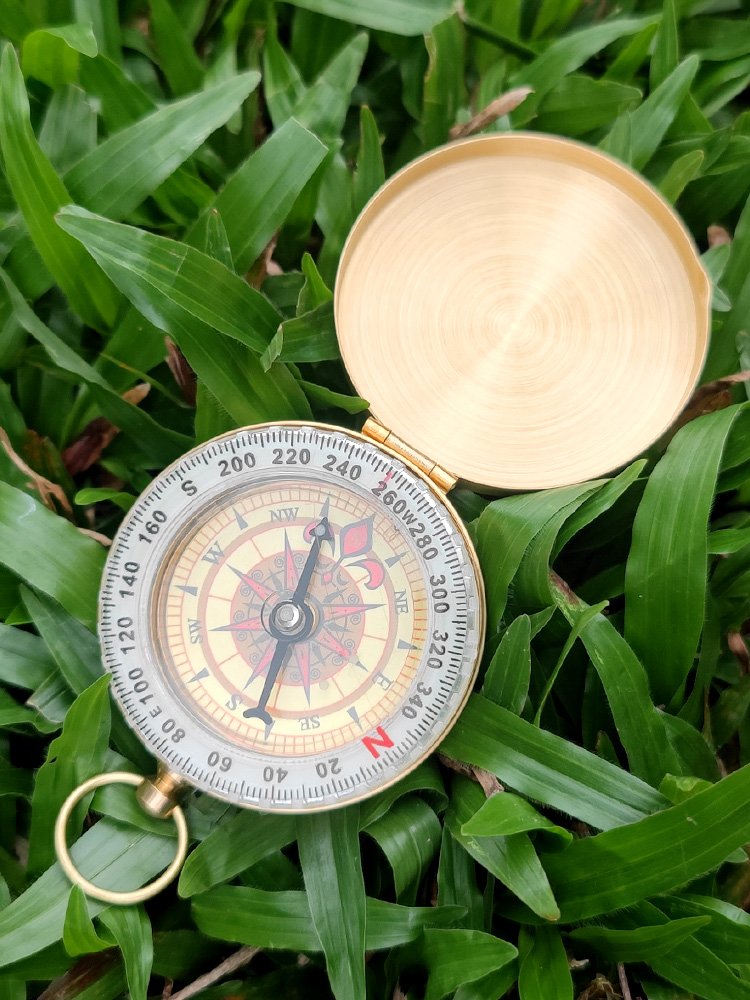 A hand-held compass with a child's high-precision sports climber with a nightlight pointer to the north needle