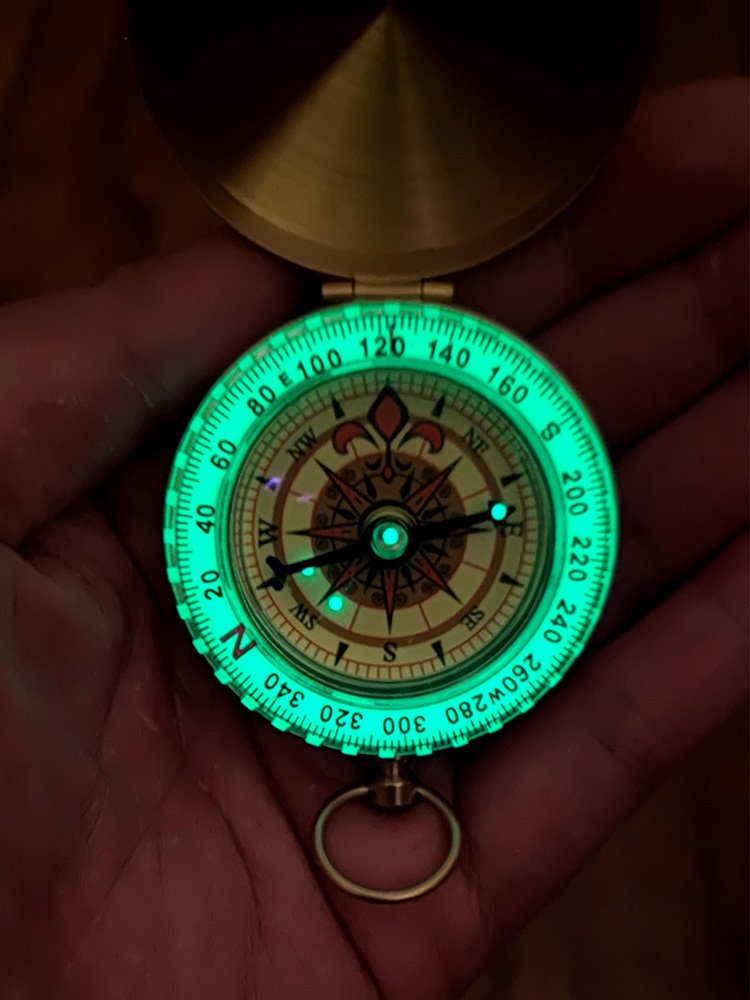 A hand-held compass with a child's high-precision sports climber with a nightlight pointer to the north needle