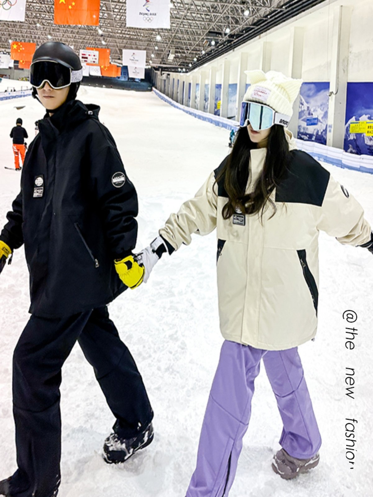 An outdoor ski suit, a man and a woman with a single, loose coat with a pair of ski pants