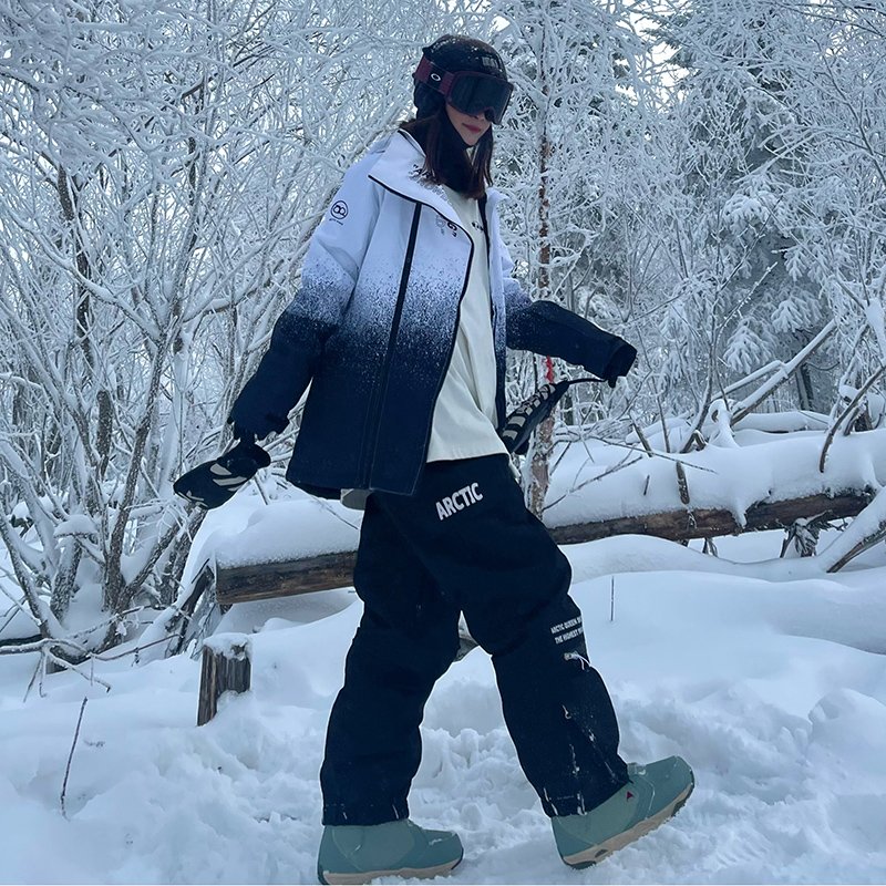 A woman in ski suit with a man in an outdoor winter weather and waterproof and thick ski pants
