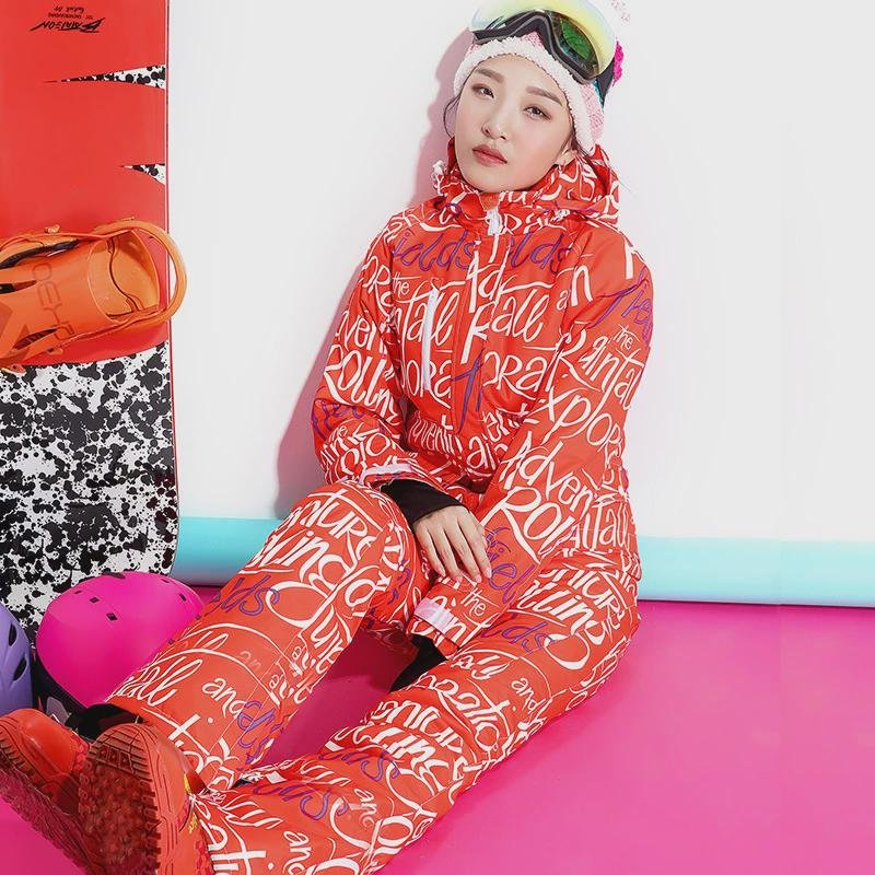 A woman in a ski suit with an adult outside to climb the mountain to protect herself from cold clothes and warm air